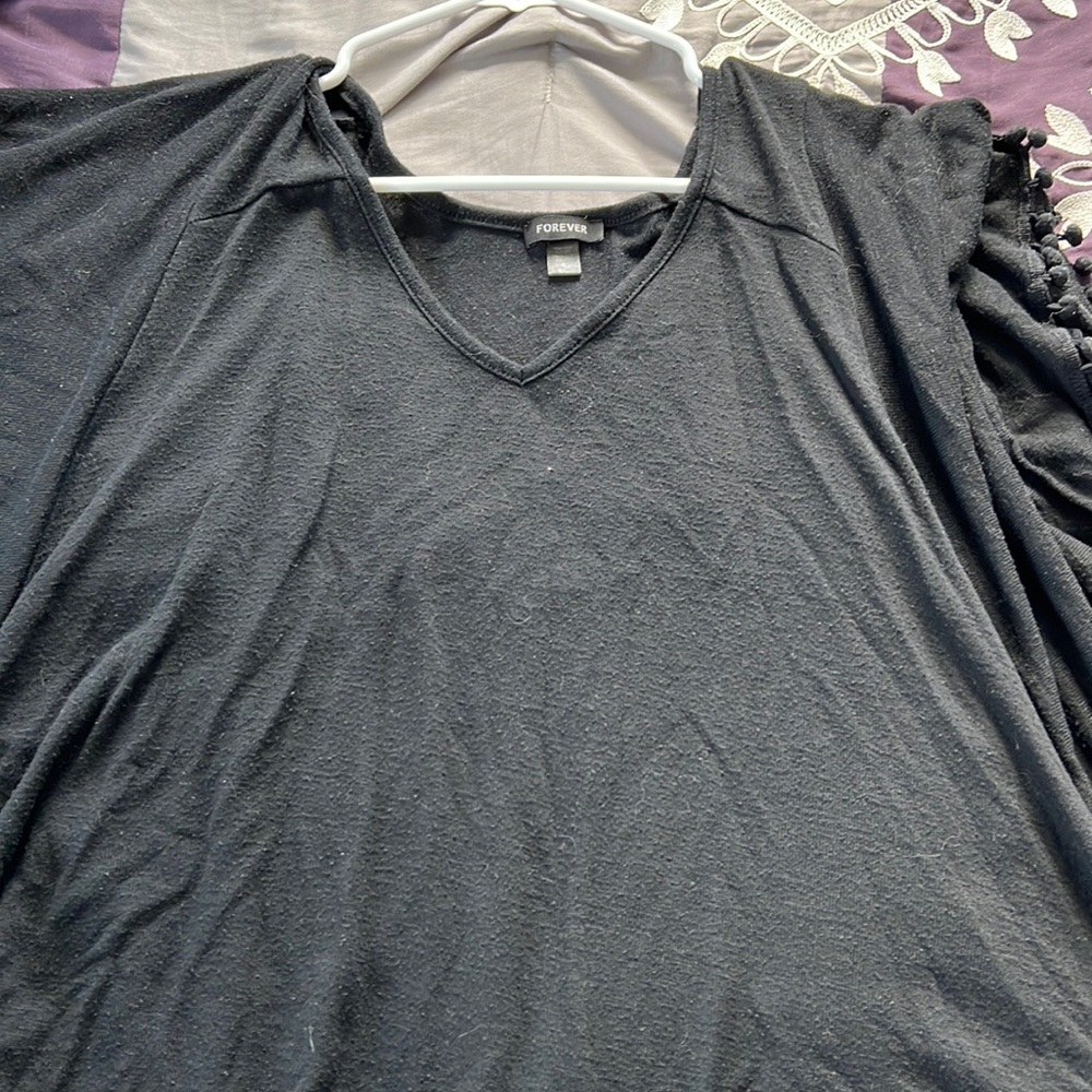 Black poncho has Pom-poms on the sleeves and bottom